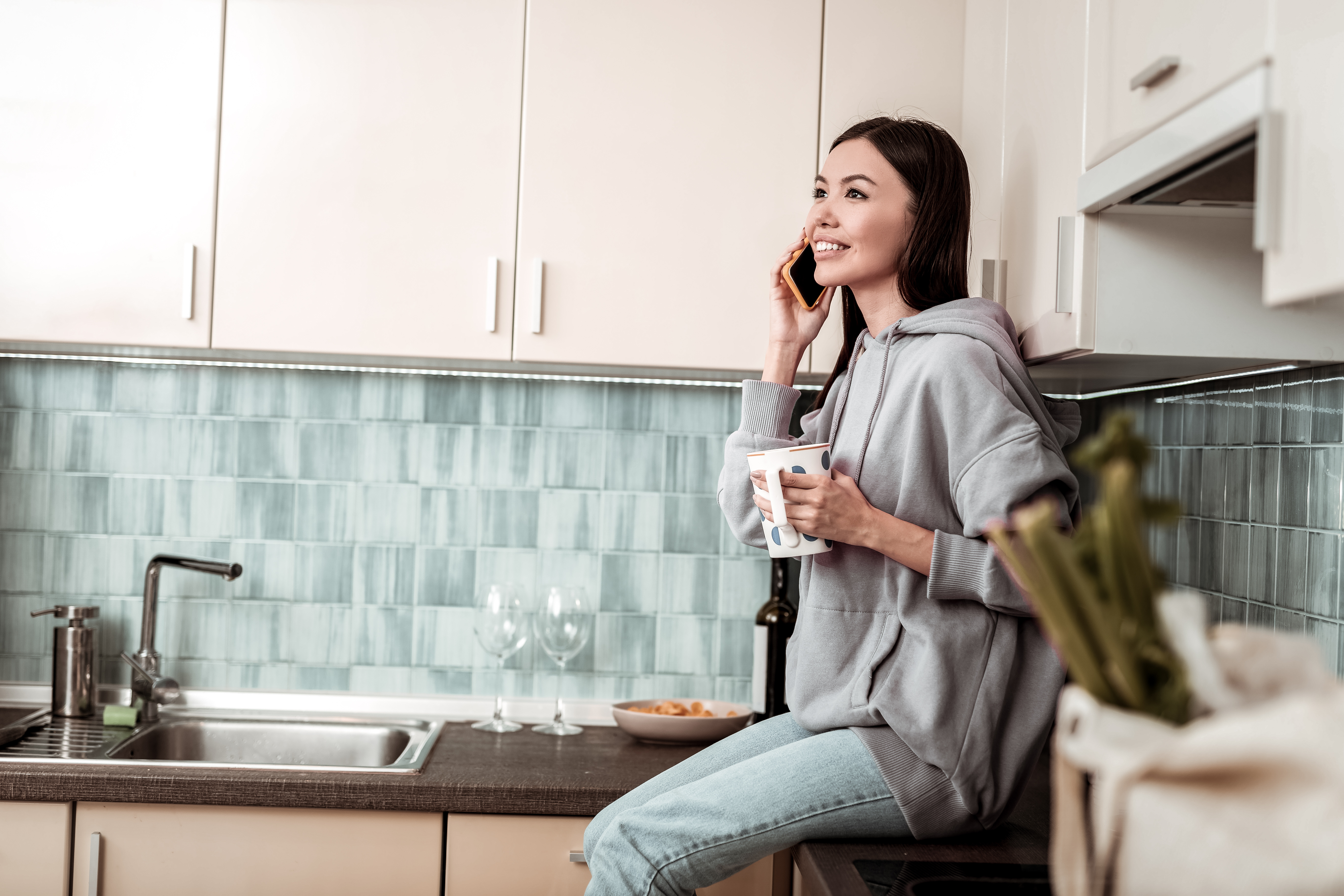 Dark-haired woman wearing oversize hoodie sitting near sink