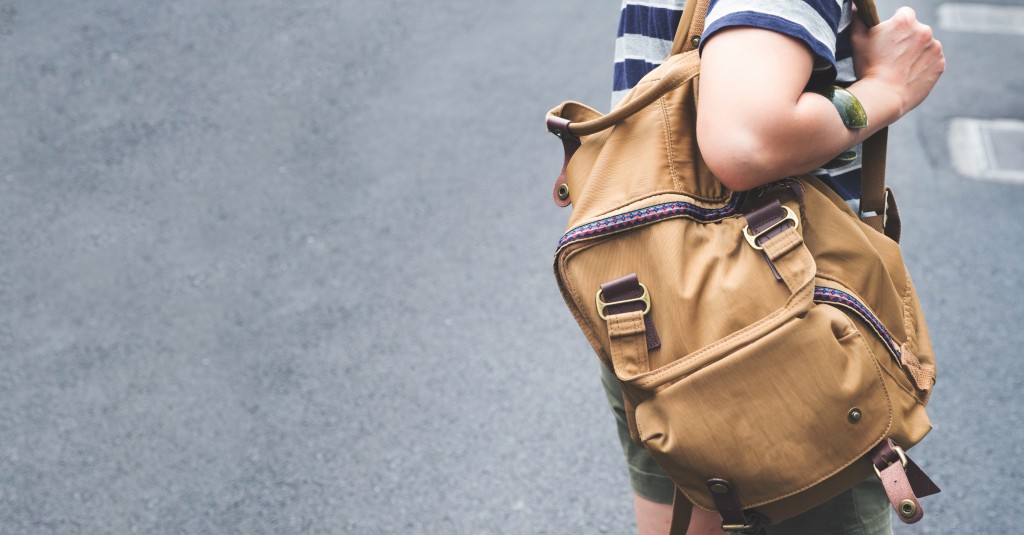 Close up backpack at back of woman traveler walking on street to sightseeing town,Travel concept,leave copy space for adding text