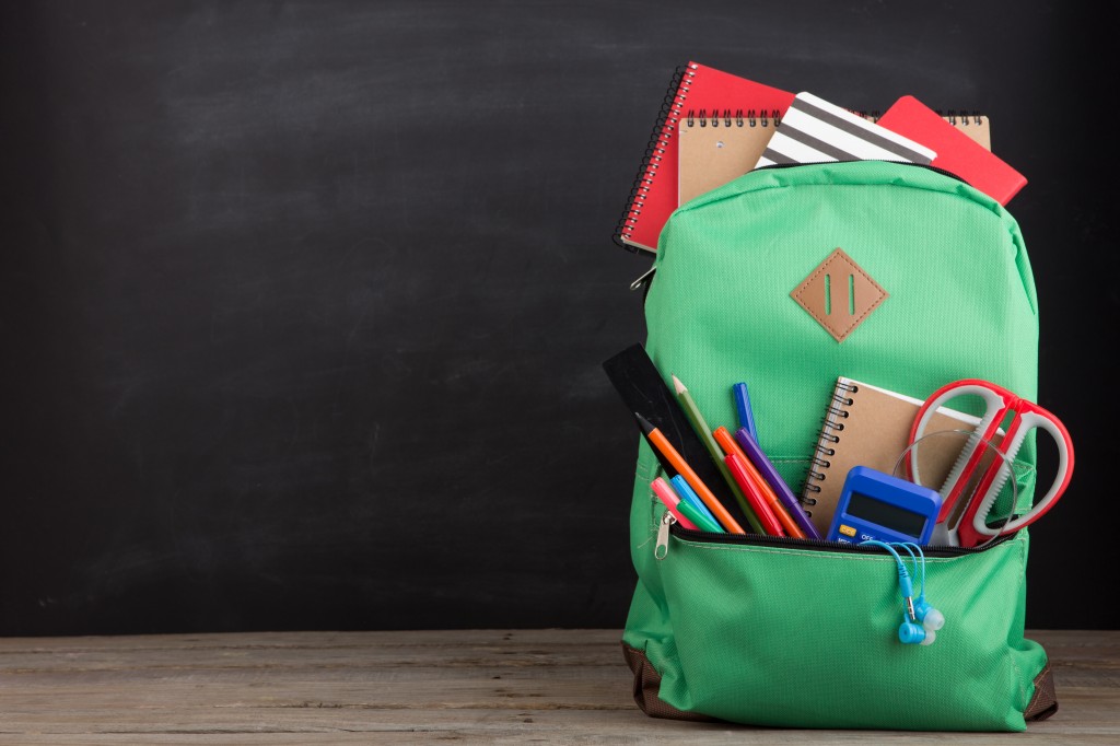 Education concept - school backpack with books and other supplies, blackboard background